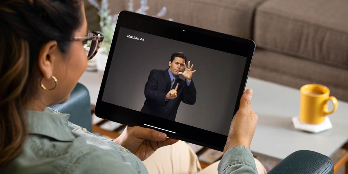 Uma irmã vendo um vídeo de um versículo da Bíblia em língua de sinais em um tablet.