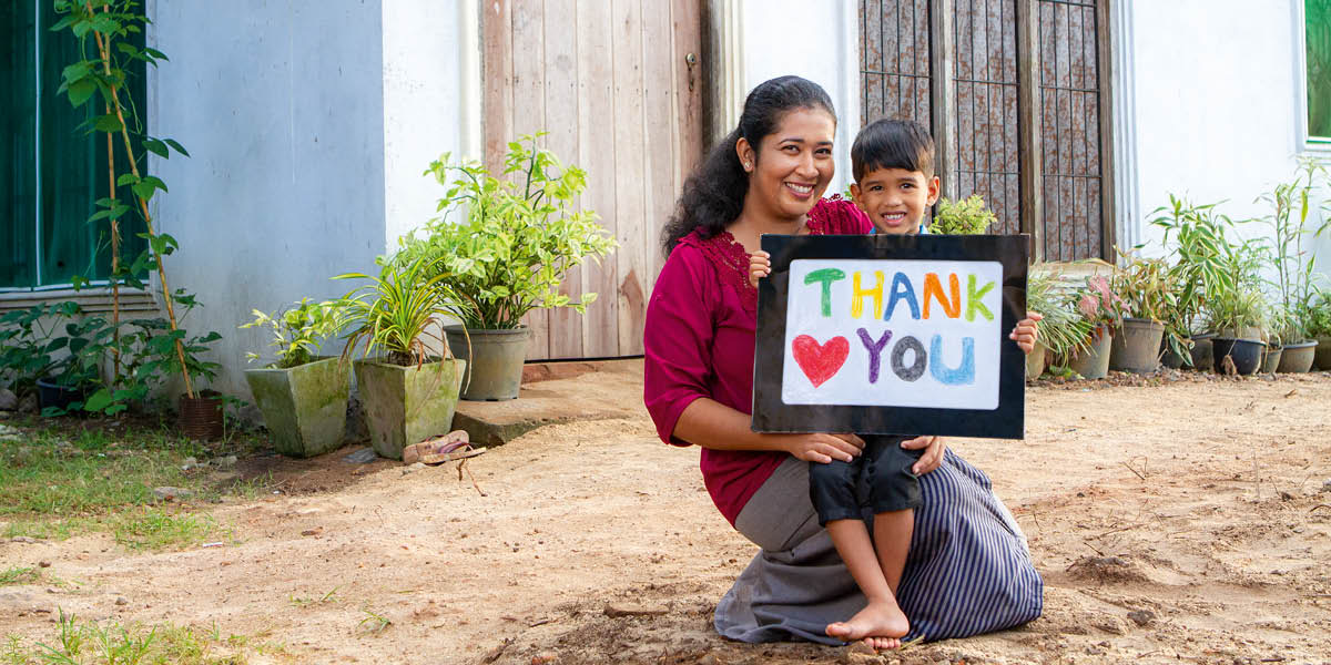 Imara Fernando com seu filhinho, Enosh. Ele está segurando um cartaz que diz: “Obrigado.”