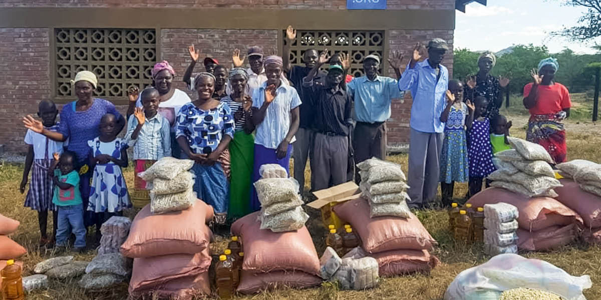 Irmãos e irmãs do lado de fora do Salão do Reino recebem alimentos da ajuda humanitária.