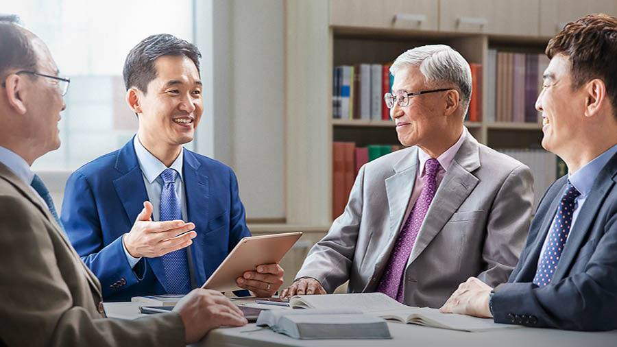 Anciãos mais velhos escutam um ancião mais novo numa reunião de anciãos.