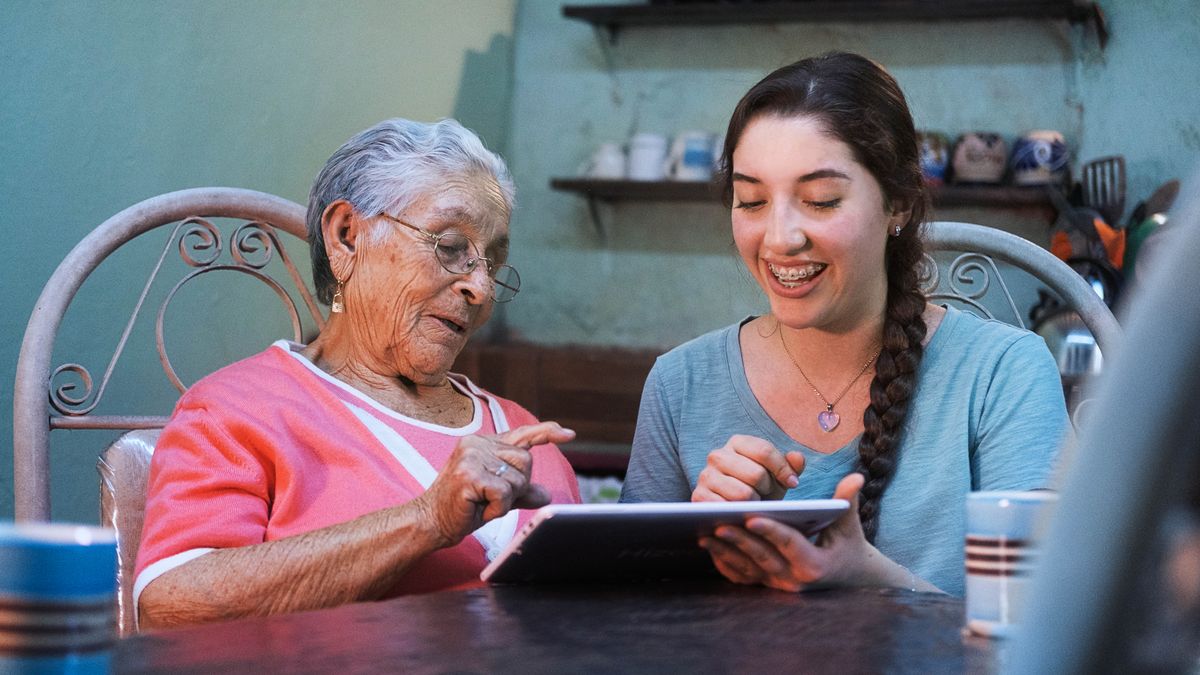 Une jeune sœur aide une sœur âgée à se servir de sa tablette.