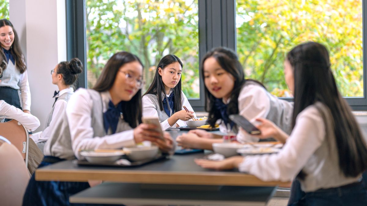 Une adolescente Témoin de Jéhovah regarde avec envie ses camarades qui papotent tout en regardant quelque chose sur un smartphone, et qui ont l’air de bien s’amuser.
