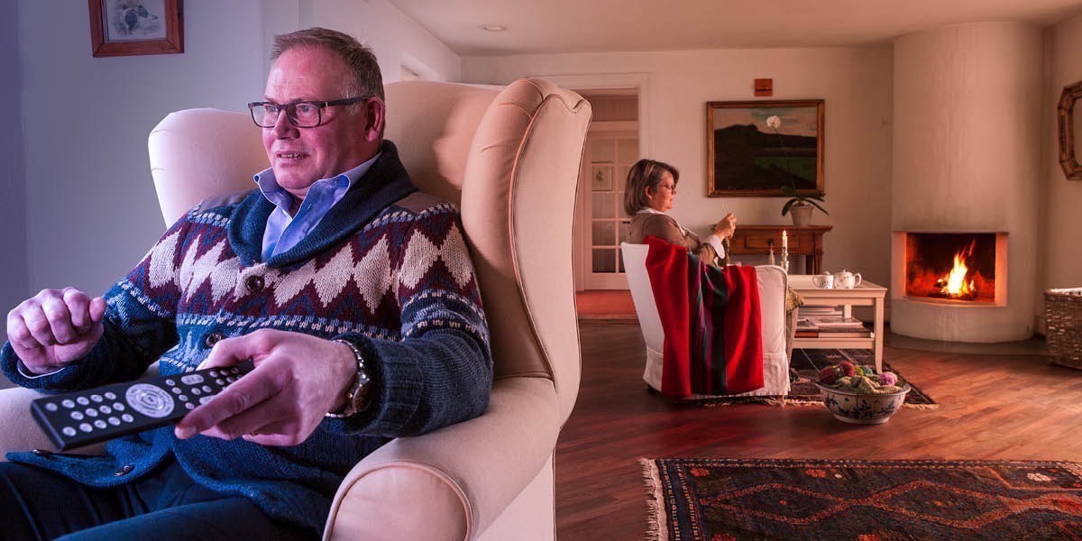 Manžel pozerá televízor v jednej miestnosti a jeho manželka sa venuje ručným prácam v druhej