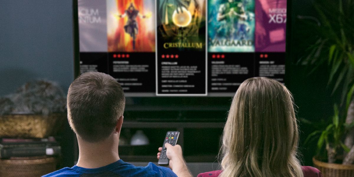 Muž so ženou pozerajú v televízii upútavky na špiritistické filmy