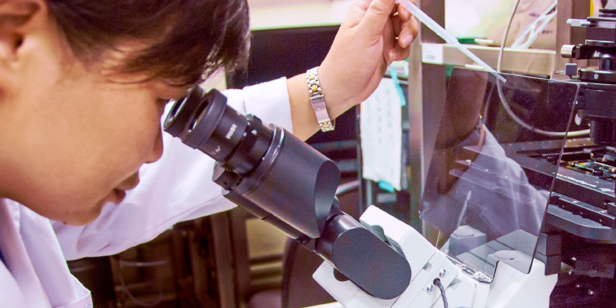 Žena sa pozerá do mikroskopu