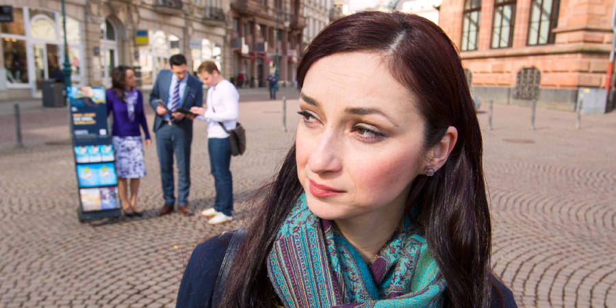 Žena sleduje Jehovových svedkov pri stojanoch s literatúrou