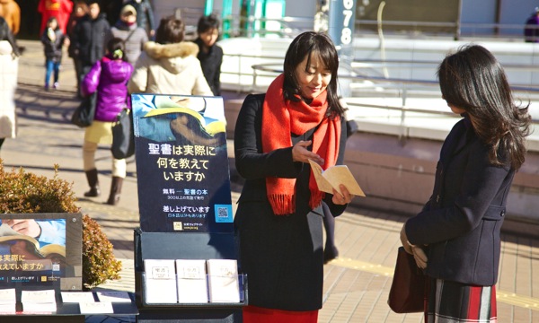 Sestra ponúka Evanjelium podľa Matúša pri stojane s literatúrou