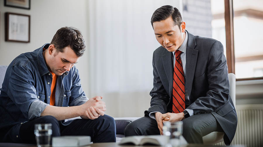 Zborový starší sa modlí s bratom, ktorý sa vrátil k Jehovovi