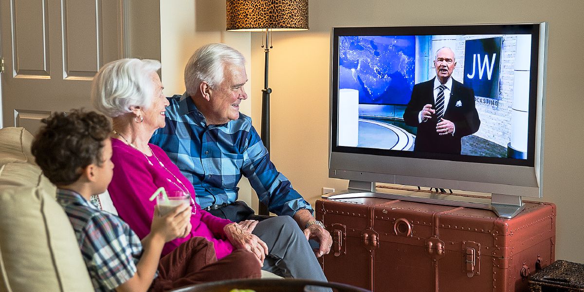 Starší manželský pár a chlapec pozerajú program na JW Broadcasting