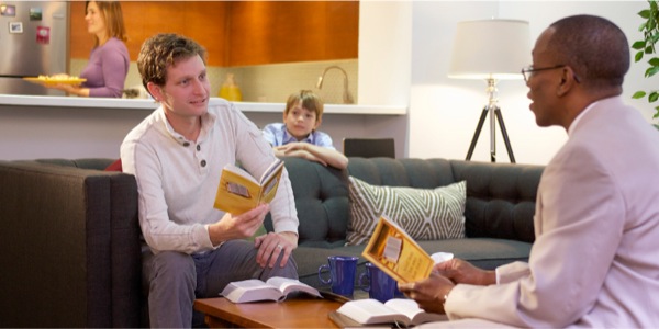 Një burrë që nuk pi më duhan, po studion Biblën; familja e tij është e lumtur