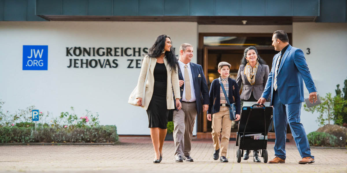 Zo sály Kráľovstva vychádza skupina zvestovateľov a jeden z nich ťahá mobilný stojan s publikáciami