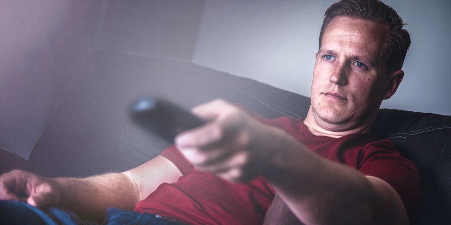 Muž sleduje televíziu a prepína kanály
