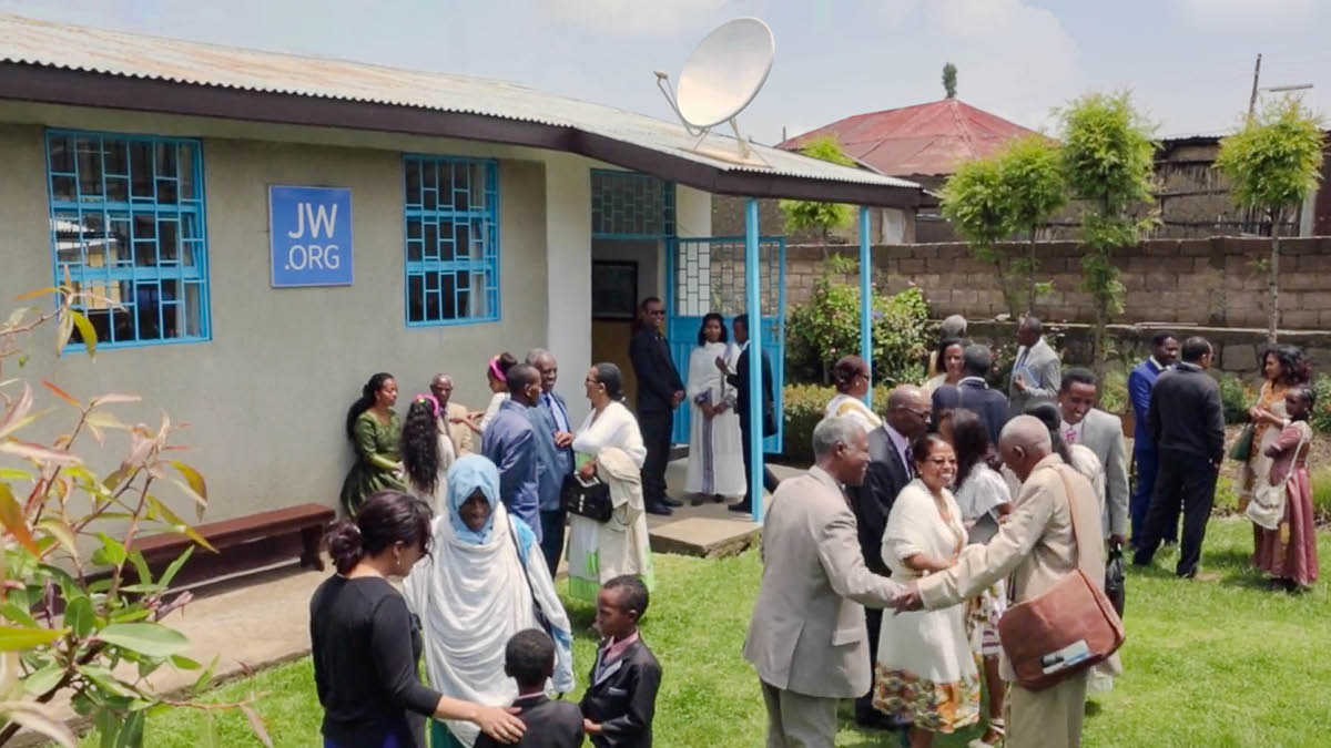 Ndugu na dada wakifurahia ushirika nje ya Jumba la Ufalme.
