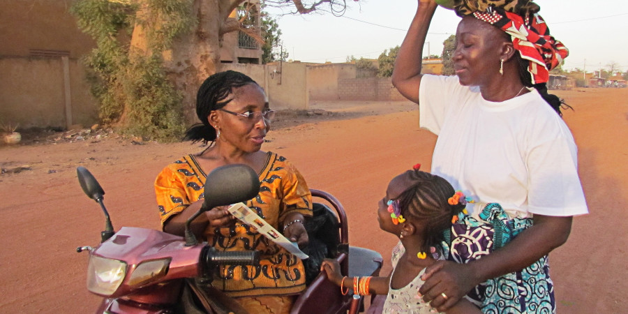 Akiwa kwenye pikipiki yake yenye magurudumu matatu, Sarah Maiga anamhubiria mwanamke pamoja na binti yake