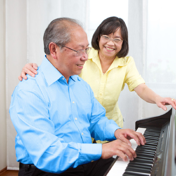 Mwanamume mzee akicheza piano huku mke wake akisikiliza
