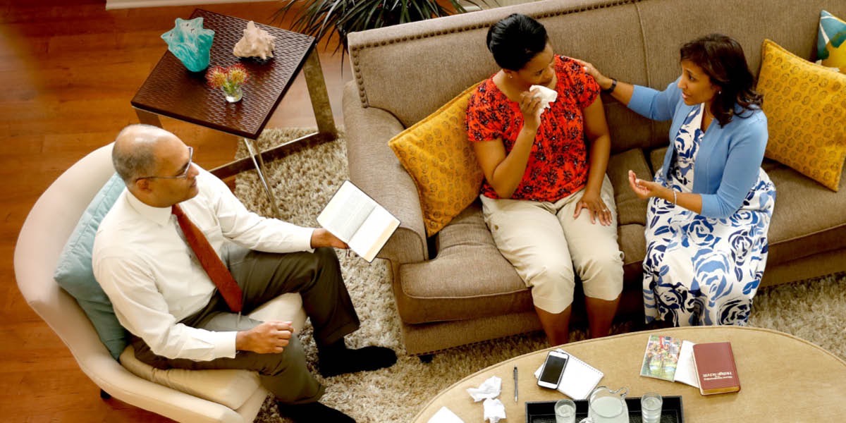 Bibi na bwana wanafariji mwanamuke mumoja kwa kutumia Biblia