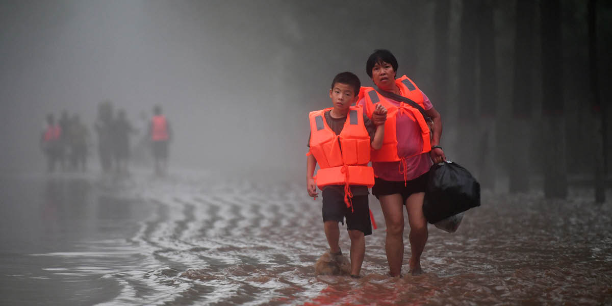 Inan ida ho ninia oan hamriik iha dalan neʼebé kona inundasaun.