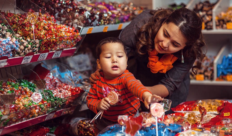 แม่​ห้าม​ลูก​เล็ก ๆ ที่​พยายาม​จะ​หยิบ​ลูก​อม​ที่​ร้าน​ขาย​ของ