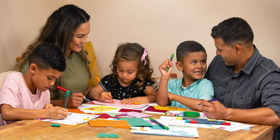 Unos papás enseñándoles a sus hijos a hacer tarjetas de agradecimiento.