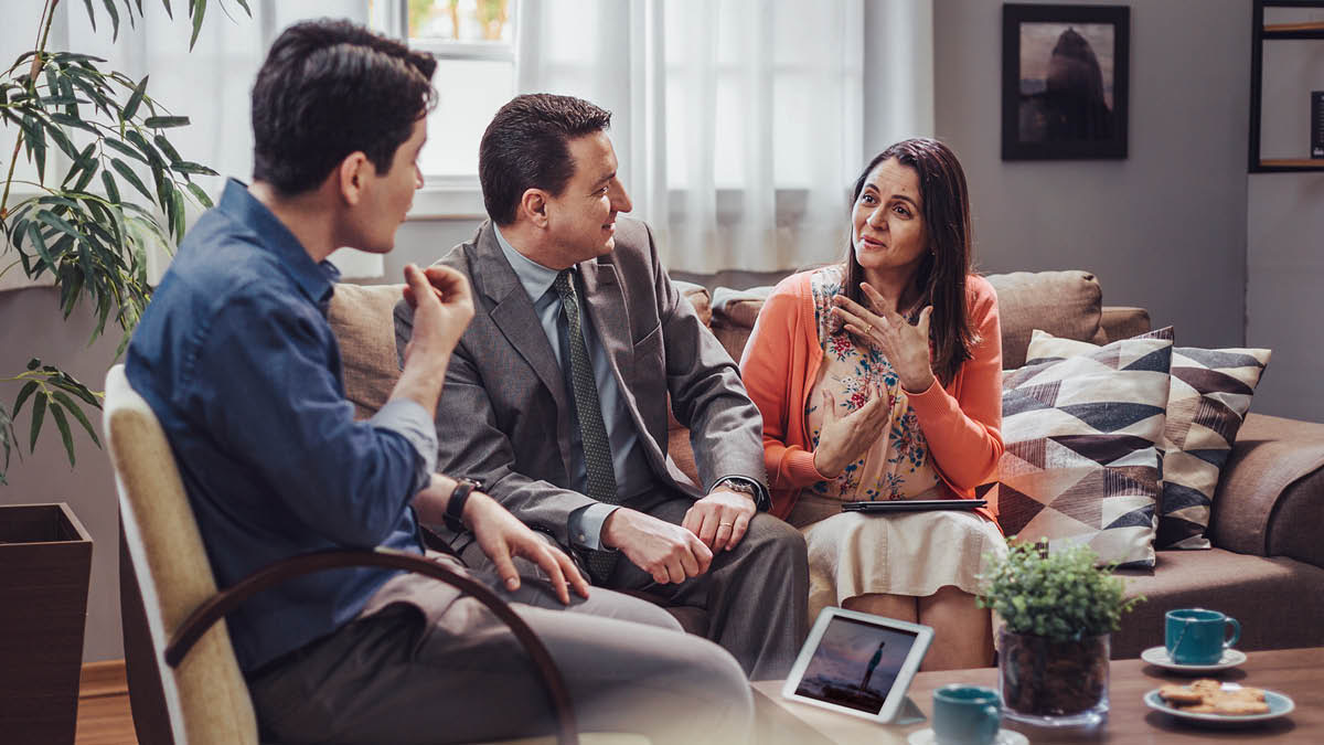 Un matrimonio de Testigos le da clases de la Biblia a un hombre con el libro “Disfrute de la vida”.
