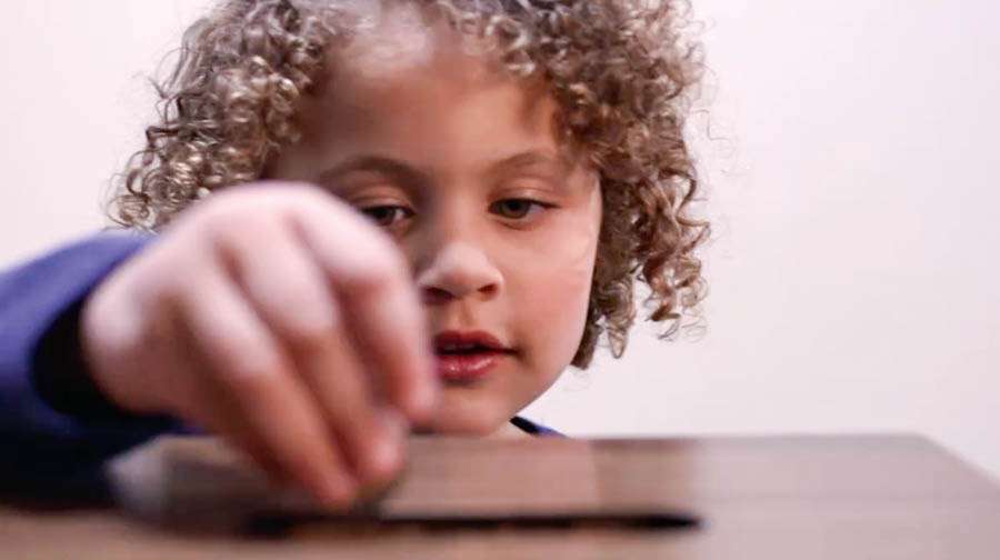 Picture from the video ‘Give Jehovah Wetin You Get.’ Small pikin wey de put money inside contribution box for Kingdom Hall.