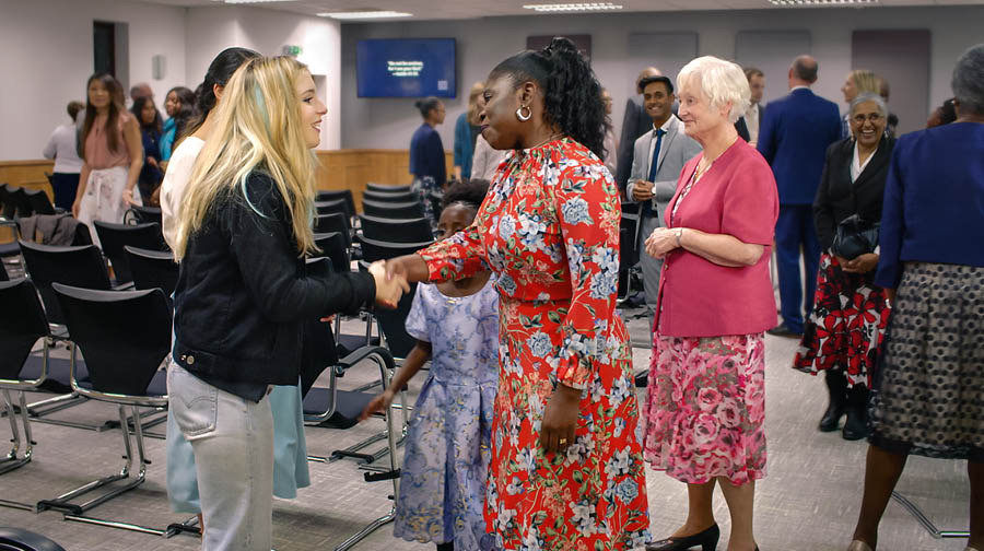 Picture from the video “Help Your Bible Students Make They Attend Meetings.” Sisters greet Jade well after meeting.