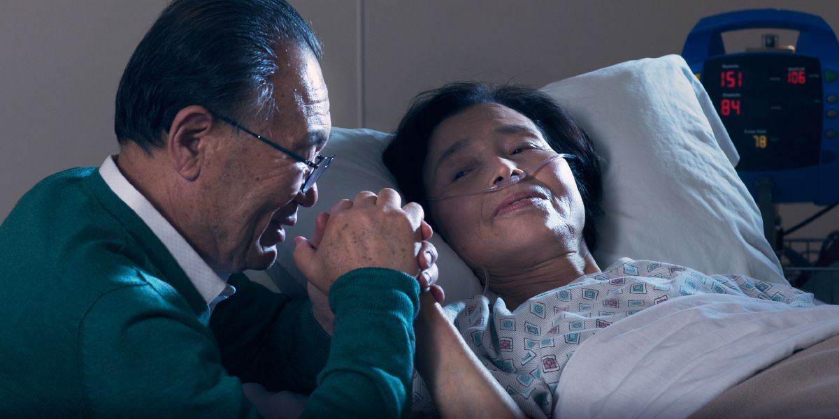 Ko he tuagaʼane ʼe takoto ʼi te lopitali; ʼe toʼo e tona ʼohoana tona nima pea nā faikole fakatahi