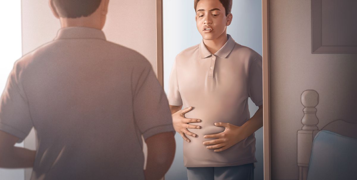 一個男孩看着鏡子中自己的肚子