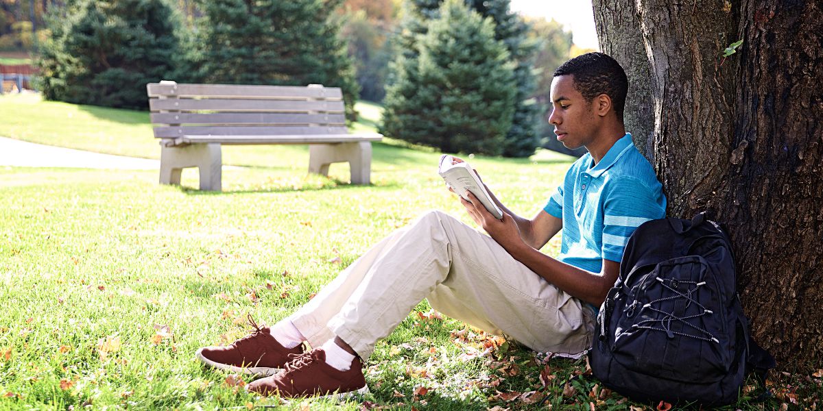 A young man sits outside and reads the Bible